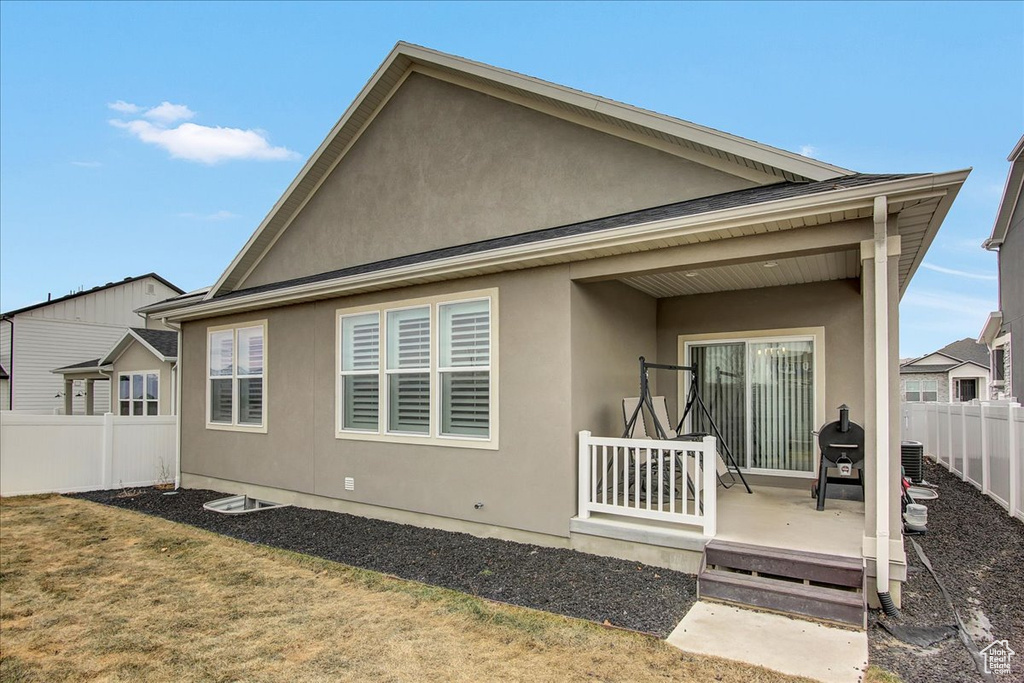 Back of property with a fenced backyard, central air condition unit, and stucco siding