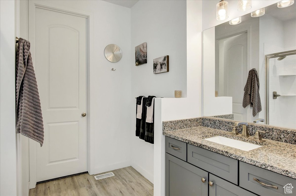 Full bathroom with visible vents, a shower with shower door, wood finished floors, vanity, and baseboards