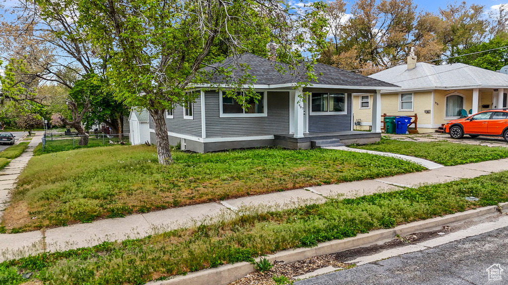 Bungalow-style house featuring a porch, a chimney, and a front lawn