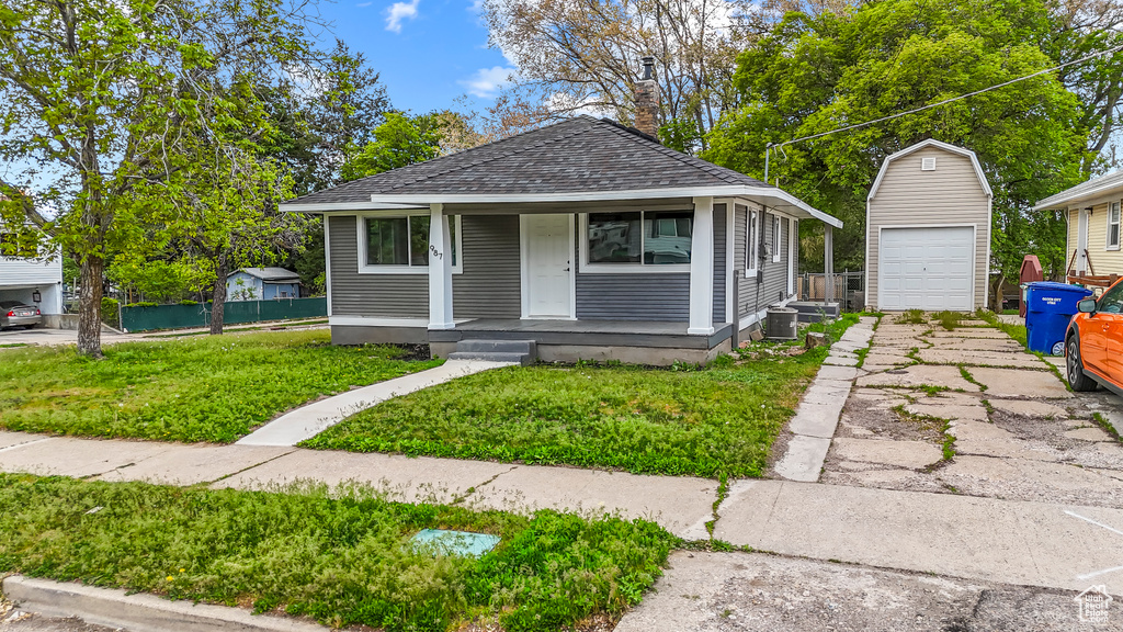 View of front facade featuring an outdoor structure, a garage, concrete driveway, a porch, and central air condition unit