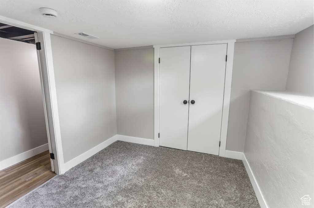 Unfurnished bedroom with a textured ceiling, visible vents, baseboards, a closet, and carpet flooring