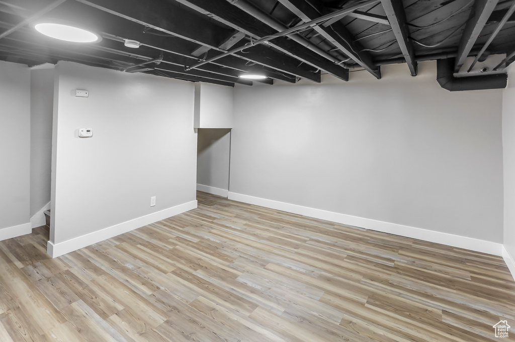 Finished below grade area featuring baseboards and light wood finished floors