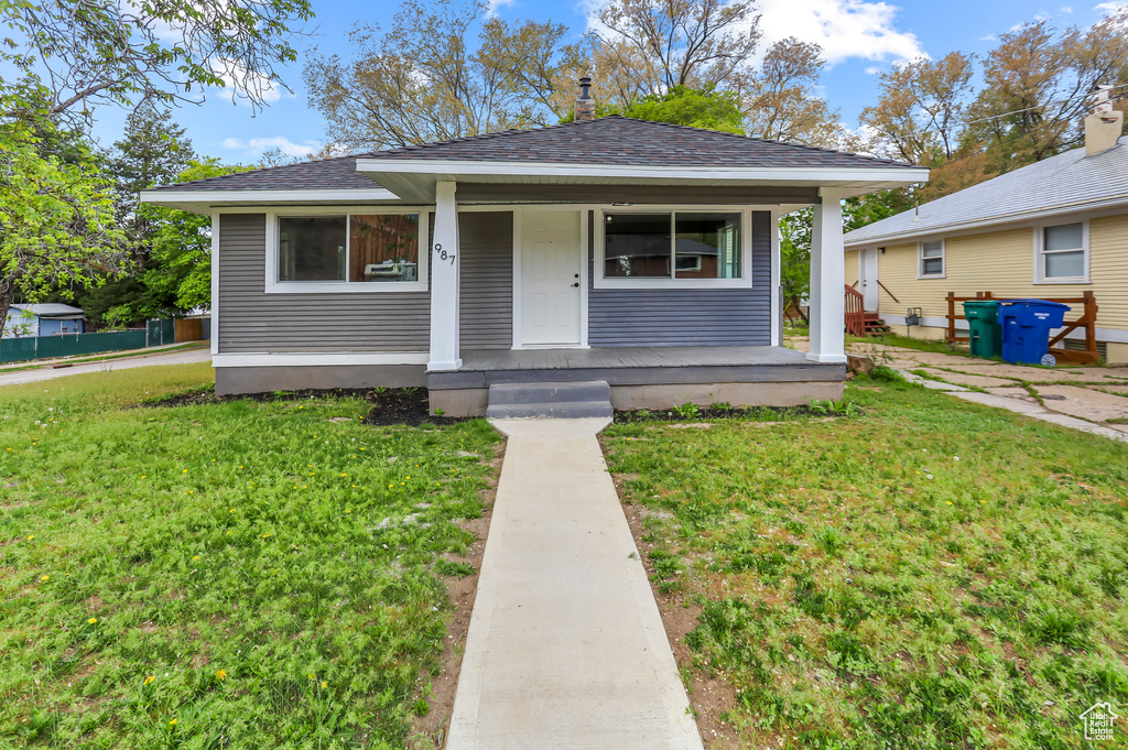 Bungalow-style home featuring a porch, roof with shingles, and a front lawn