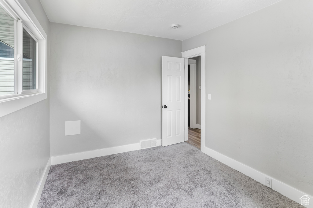 Empty room with baseboards, carpet flooring, and visible vents