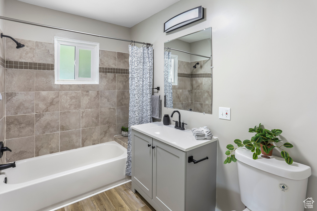 Bathroom with toilet, wood finished floors, shower / bath combo, and vanity