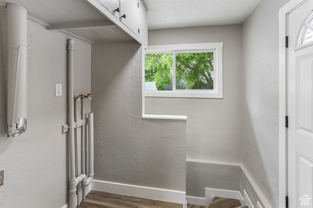 Clothes washing area featuring baseboards, cabinet space, and wood finished floors
