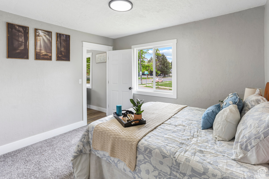 Carpeted bedroom featuring a textured ceiling and baseboards