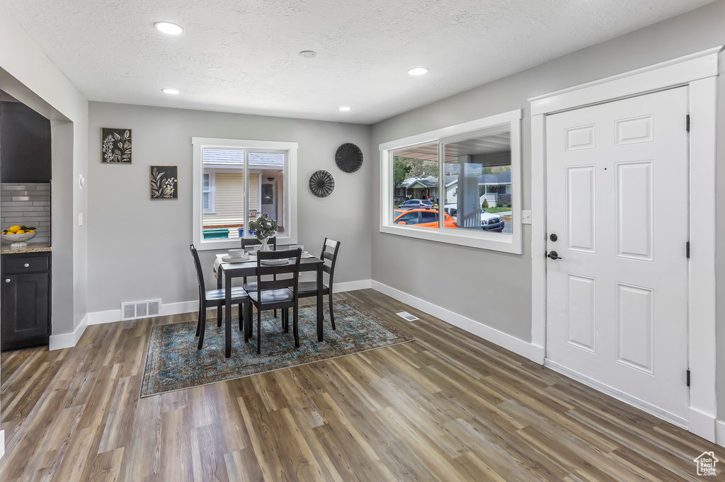 Dining space with a textured ceiling, recessed lighting, wood finished floors, and visible vents
