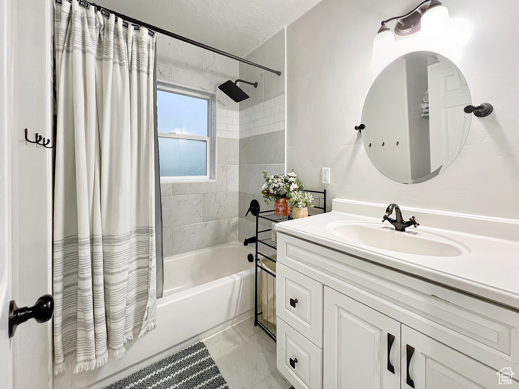 Bathroom with vanity, marble finish floor, and shower / tub combo