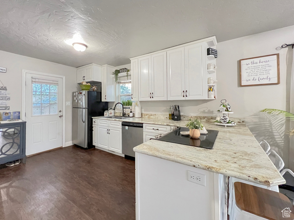 Kitchen with white cabinets, stainless steel appliances, a healthy amount of sunlight, and a peninsula