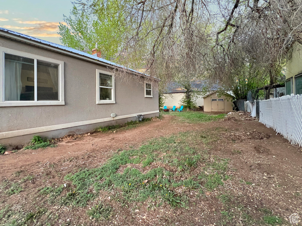 View of yard with a storage shed, fence, and an outbuilding