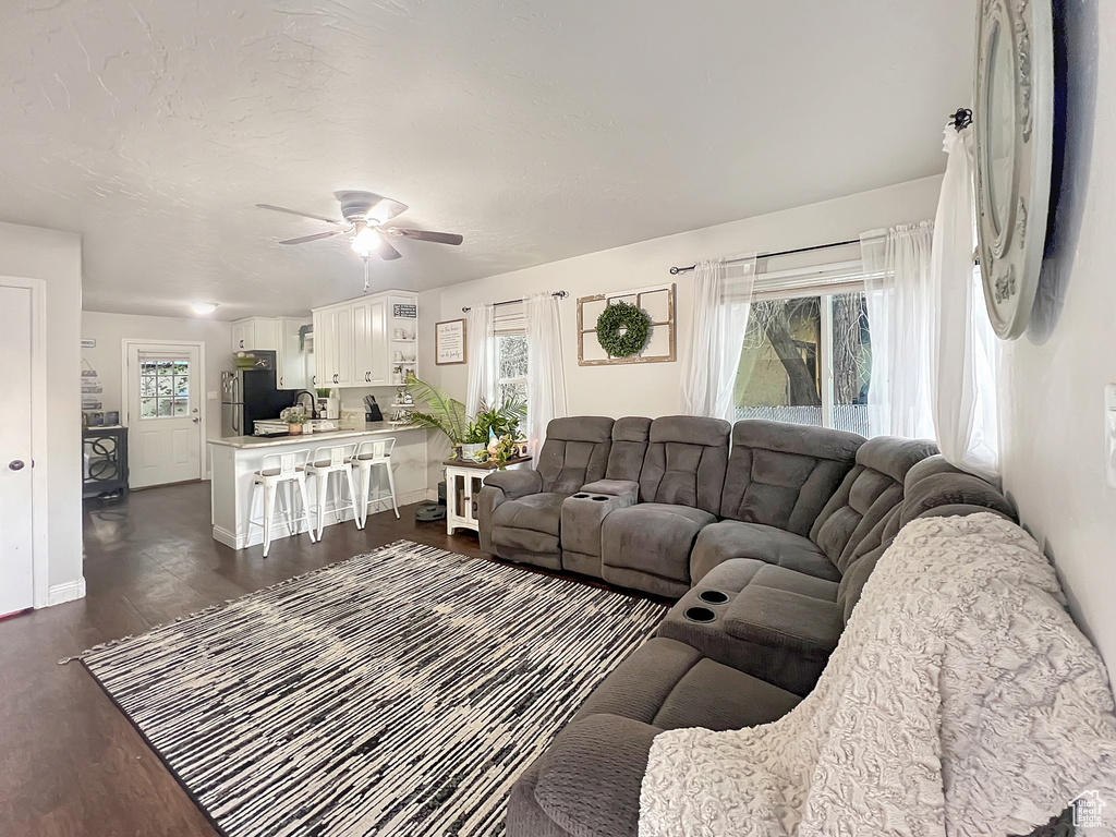 Living area featuring baseboards, ceiling fan, and dark wood-style flooring