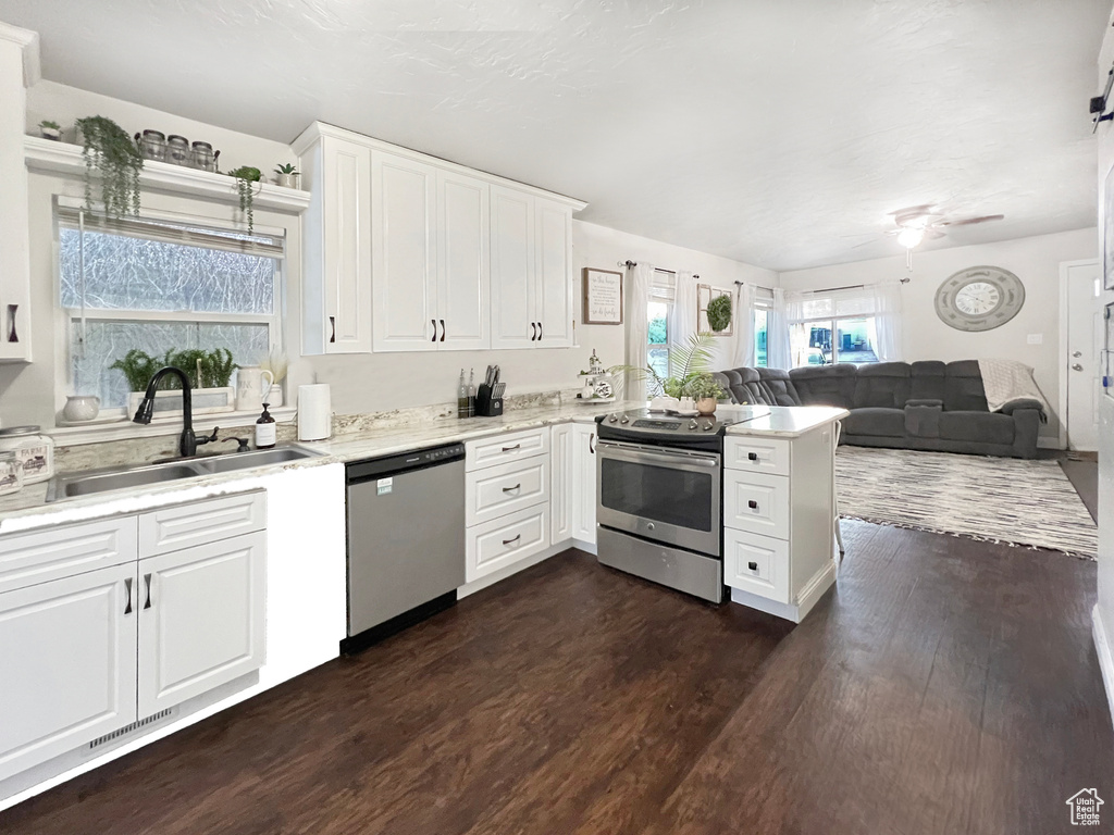 Kitchen with a sink, dark wood finished floors, stainless steel appliances, open floor plan, and a peninsula