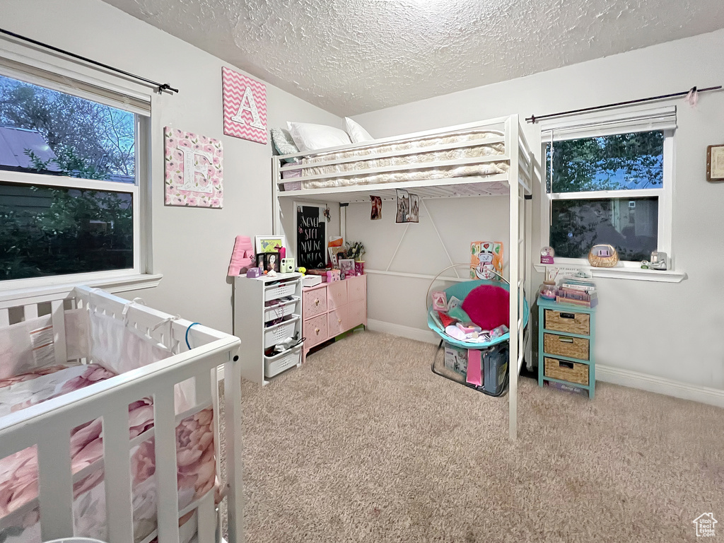 Carpeted bedroom with a textured ceiling and baseboards