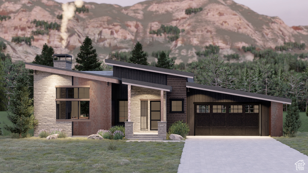 Modern home with a front yard, a mountain view, and stone siding