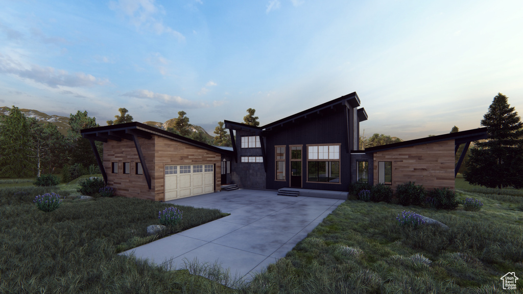 View of front of house with concrete driveway, an attached garage, an outbuilding, and a front lawn