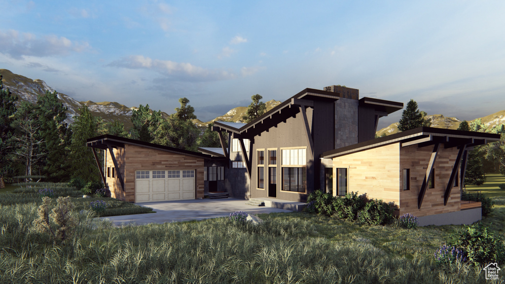Contemporary house featuring an outdoor structure, an attached garage, concrete driveway, and a mountain view