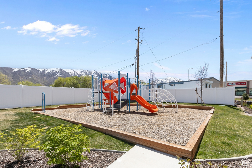Community play area featuring fence, a mountain view, and a lawn