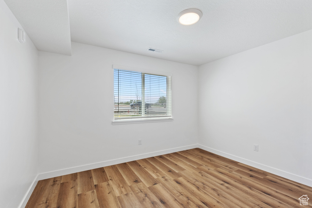 Unfurnished room featuring light wood-style floors, baseboards, and visible vents