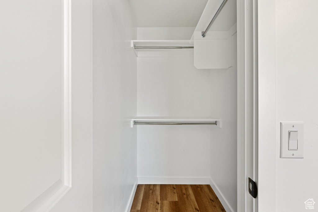 Walk in closet with dark wood-style floors