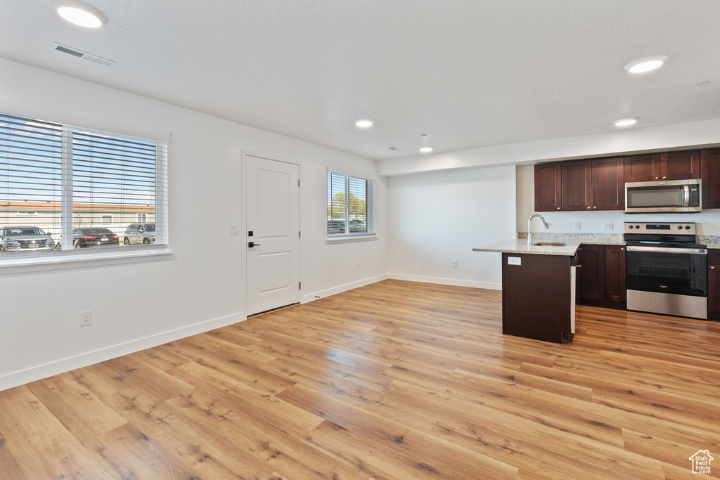 Kitchen featuring visible vents, dark brown cabinets, a sink, baseboards, and stainless steel appliances