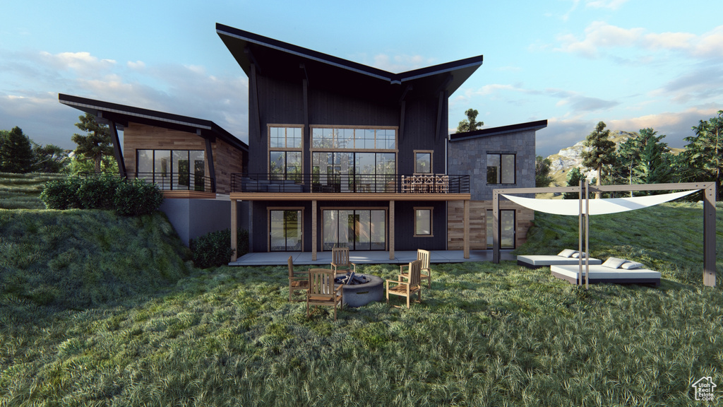 Rear view of property featuring a yard, a patio, and a balcony