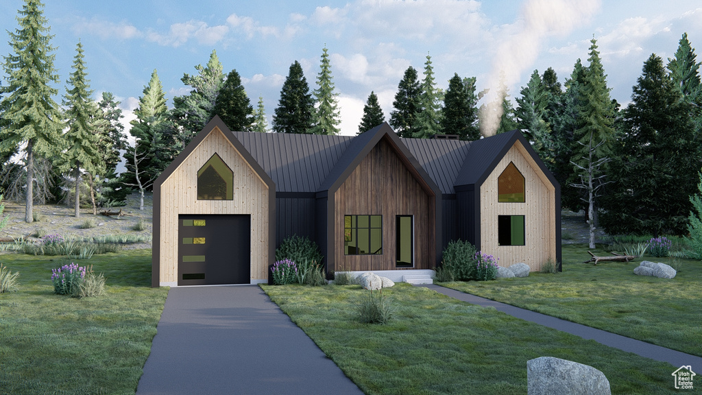 View of front of property with a garage, driveway, metal roof, and a front lawn