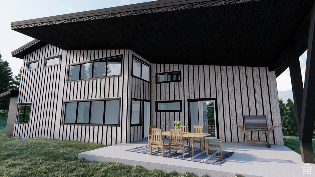 Back of property with board and batten siding, a yard, and a patio area