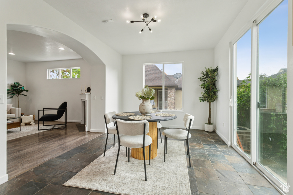 Dining space featuring stone tile floors, arched walkways, healthy amount of natural light, a chandelier, and recessed lighting