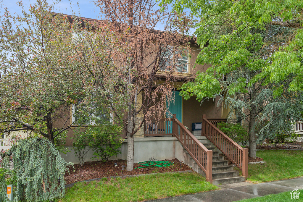 Obstructed view of property featuring stucco siding, stairs, and a front lawn