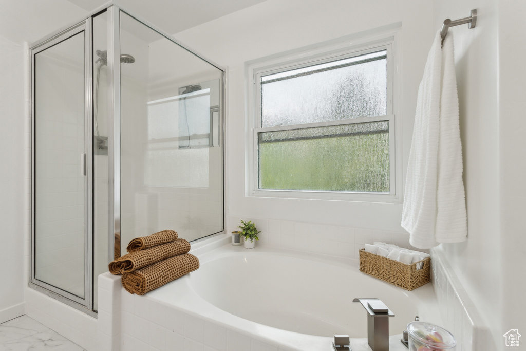 Full bathroom with a shower stall, a bath, and marble look tiles