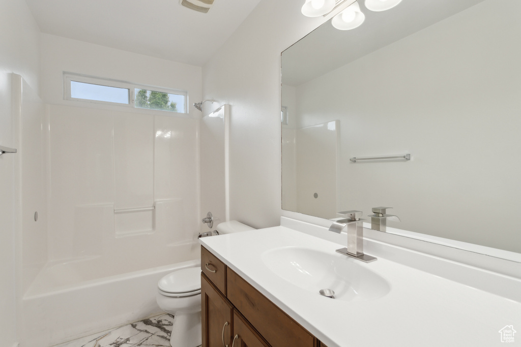 Bathroom featuring toilet, vanity, and bathtub / shower combination
