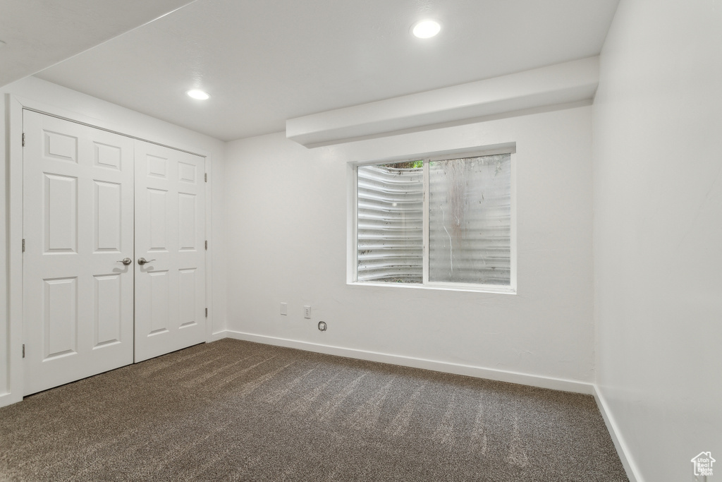 Unfurnished bedroom featuring dark carpet, baseboards, recessed lighting, and a closet