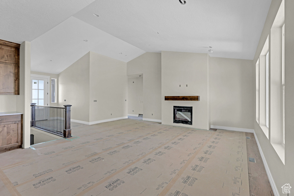 Unfurnished living room featuring baseboards, a fireplace, and lofted ceiling