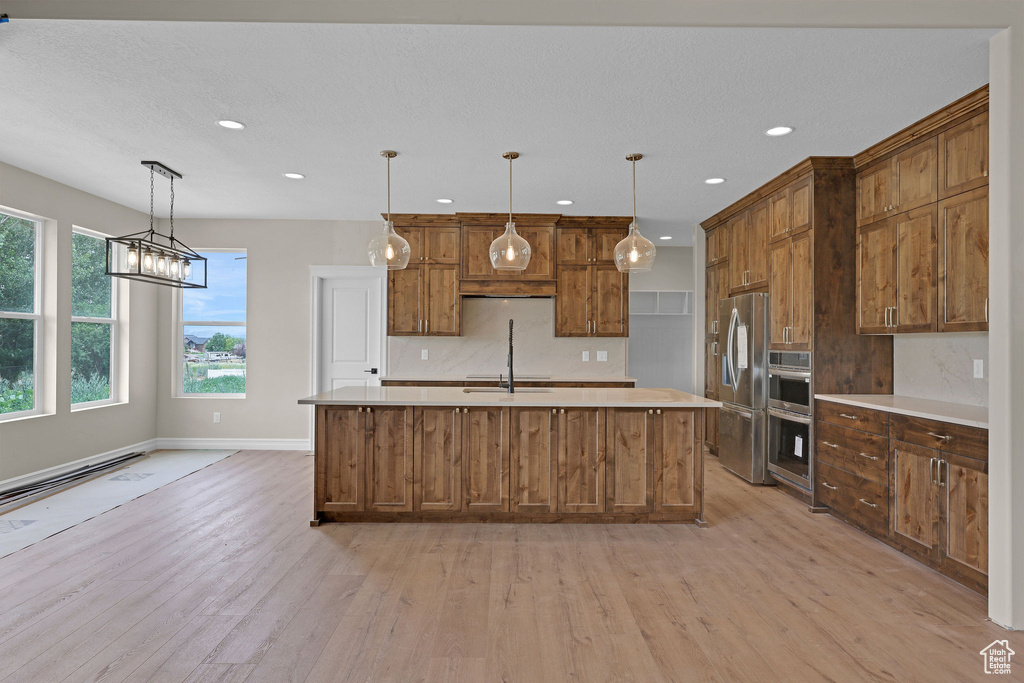 Kitchen with stainless steel appliances, light wood-type flooring, light countertops, recessed lighting, and backsplash