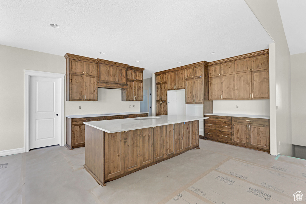 Kitchen with brown cabinets, light countertops, baseboards, and a center island