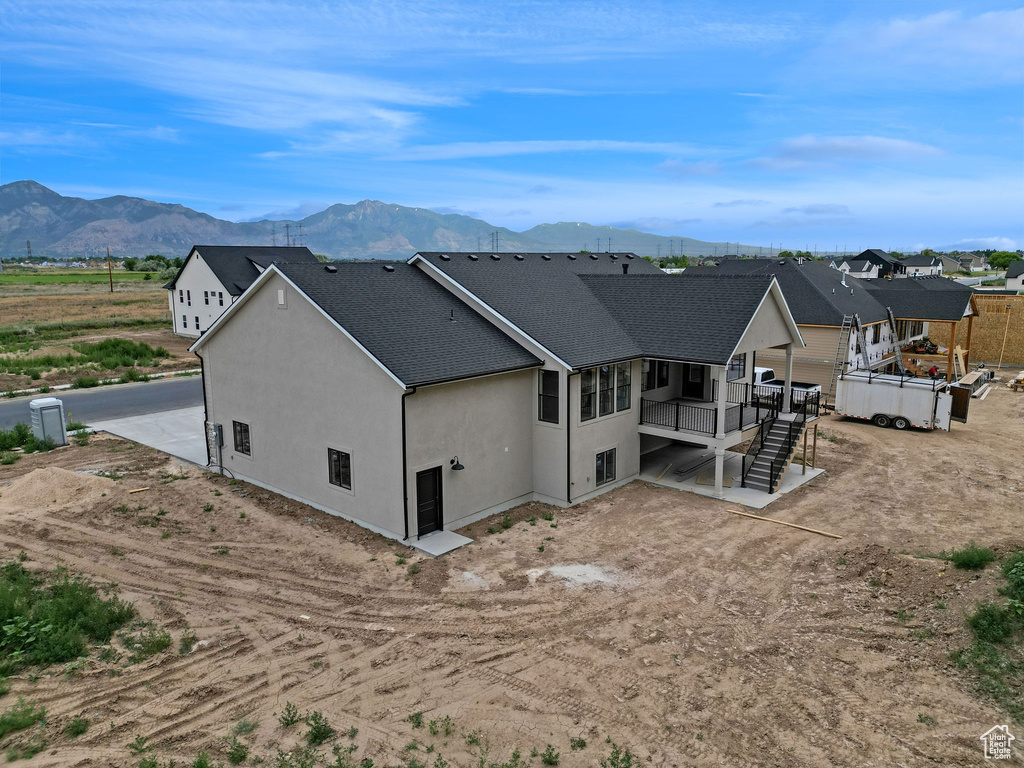 Rear view of property with a mountain view, stucco siding, roof with shingles, and stairway
