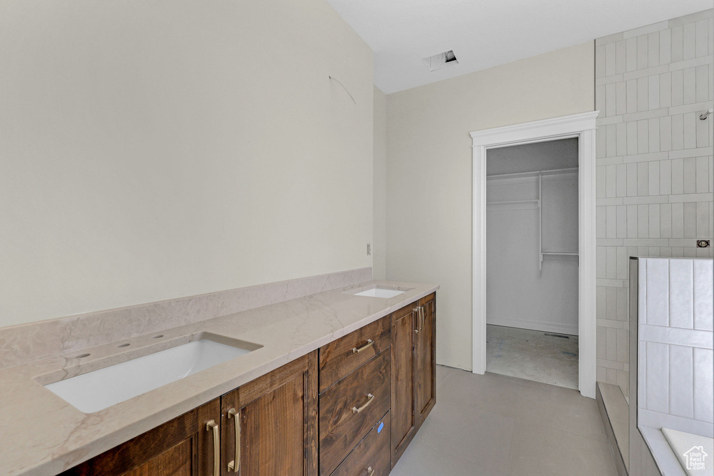 Bathroom with a sink, a walk in closet, and visible vents