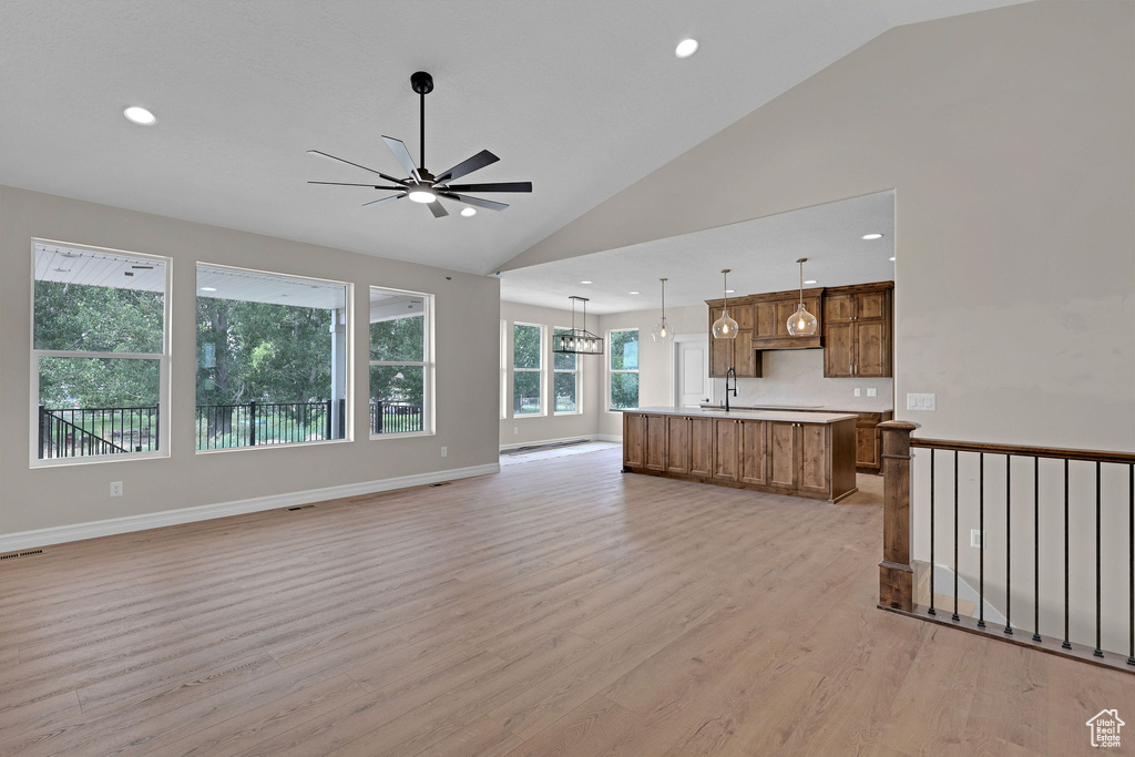 Unfurnished living room with a ceiling fan, light wood finished floors, recessed lighting, and high vaulted ceiling