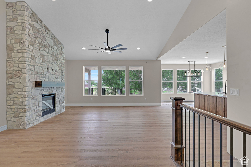 Unfurnished living room with ceiling fan, wood finished floors, plenty of natural light, a stone fireplace, and recessed lighting