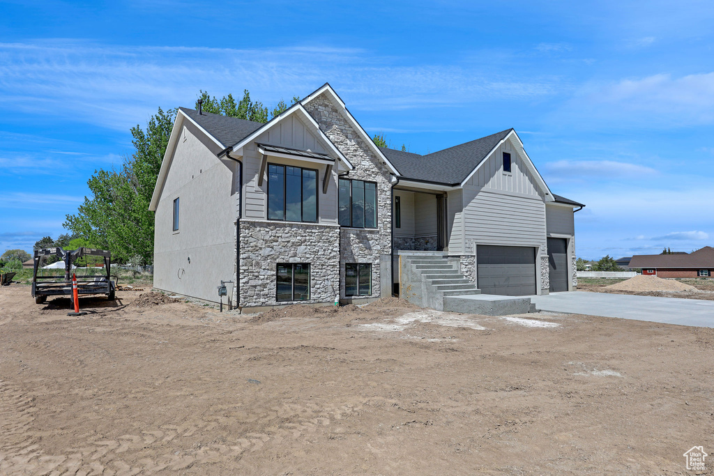 Craftsman-style house with concrete driveway, board and batten siding, an attached garage, and stone siding