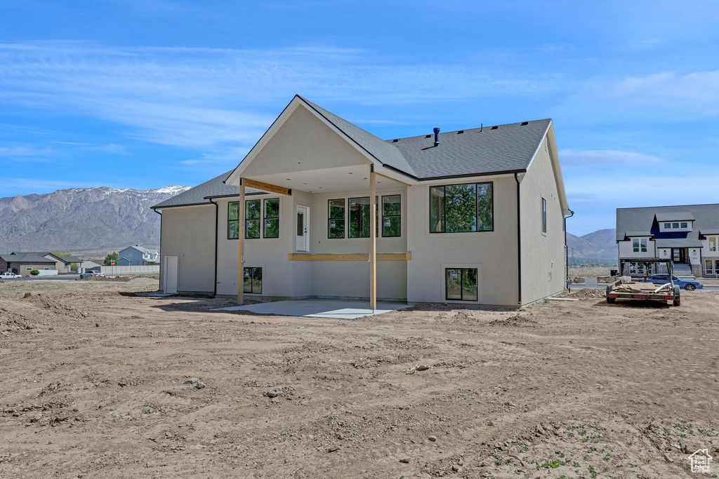Rear view of property featuring a patio, roof with shingles, a mountain view, and stucco siding