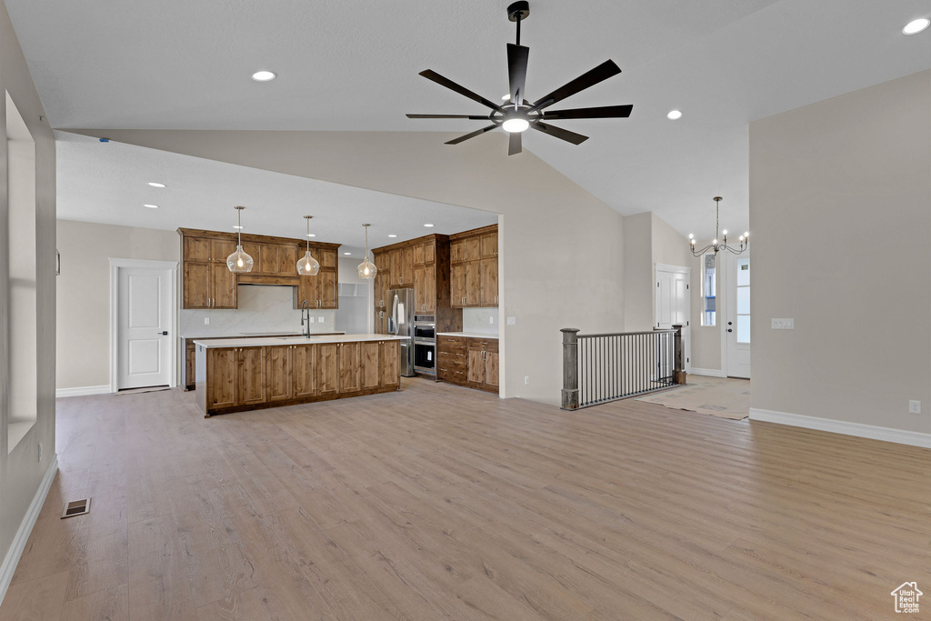 Unfurnished living room featuring light wood-style flooring, a chandelier, recessed lighting, a ceiling fan, and high vaulted ceiling