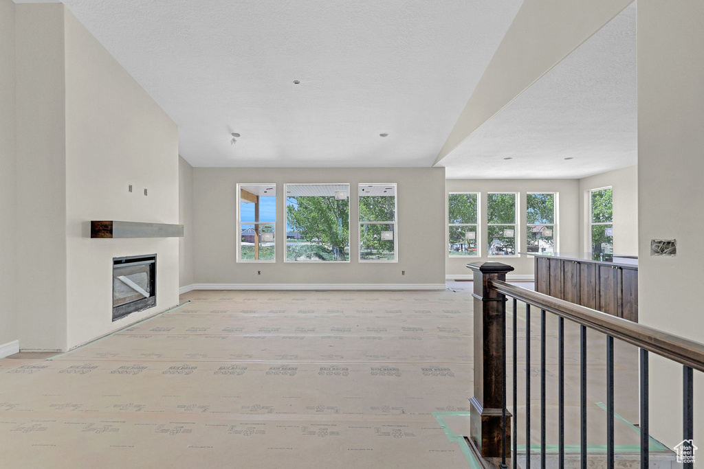 Unfurnished living room featuring baseboards and a glass covered fireplace
