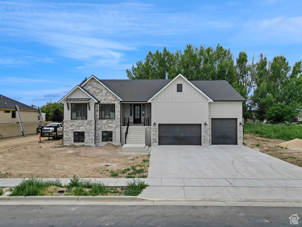 View of front of house featuring stone siding, board and batten siding, an attached garage, and concrete driveway