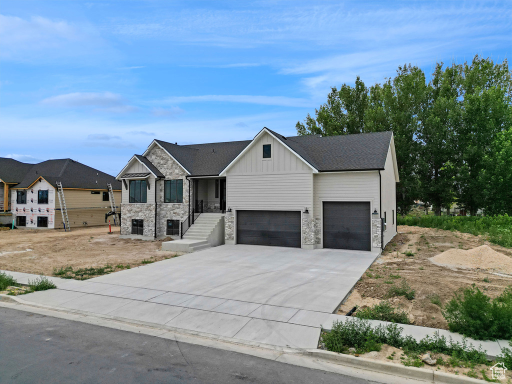 View of front of home with board and batten siding, a garage, concrete driveway, and stone siding