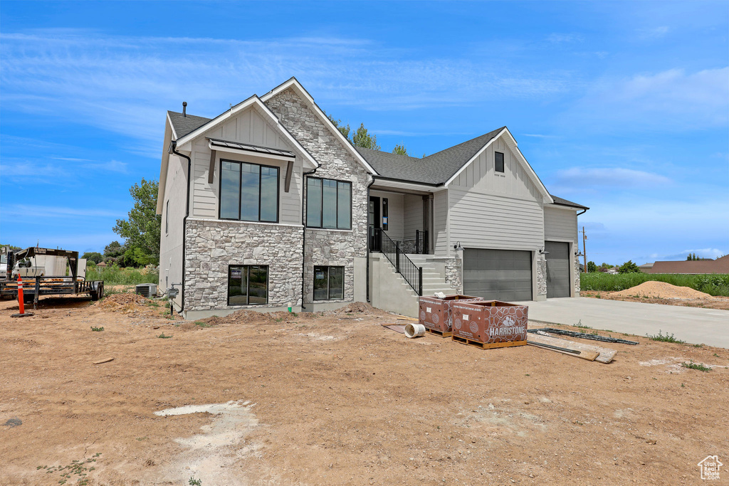 Modern home featuring board and batten siding, stone siding, an attached garage, and concrete driveway