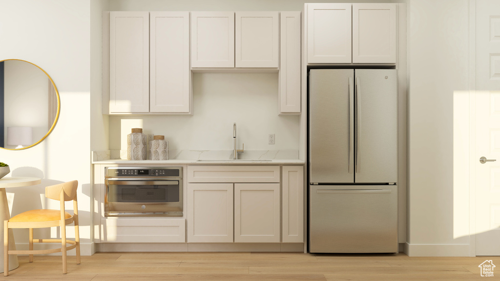 Kitchen featuring freestanding refrigerator, a sink, light wood-style flooring, and oven