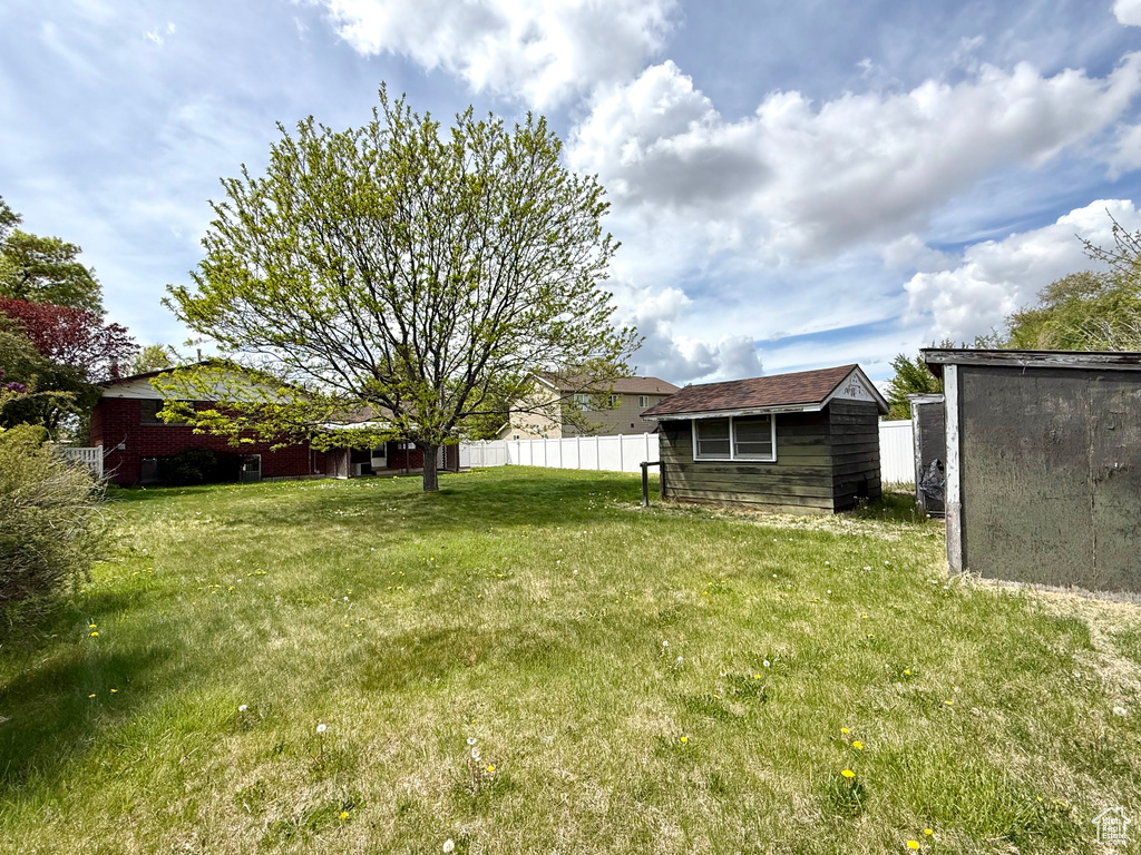 View of yard featuring fence, an outbuilding, and a shed