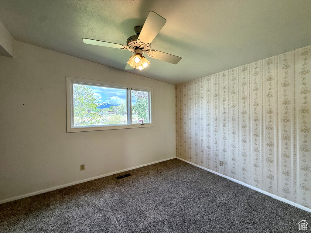 Spare room featuring carpet flooring, ceiling fan, visible vents, and baseboards